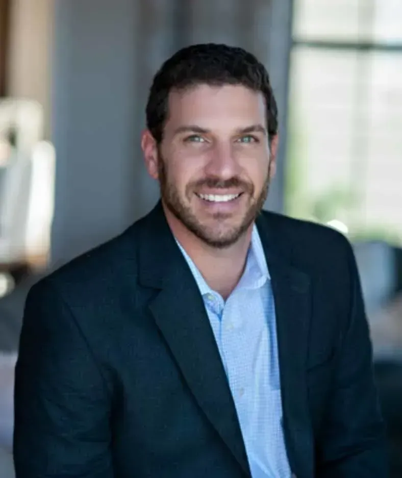 A man in a suit and blue shirt is smiling for the camera.