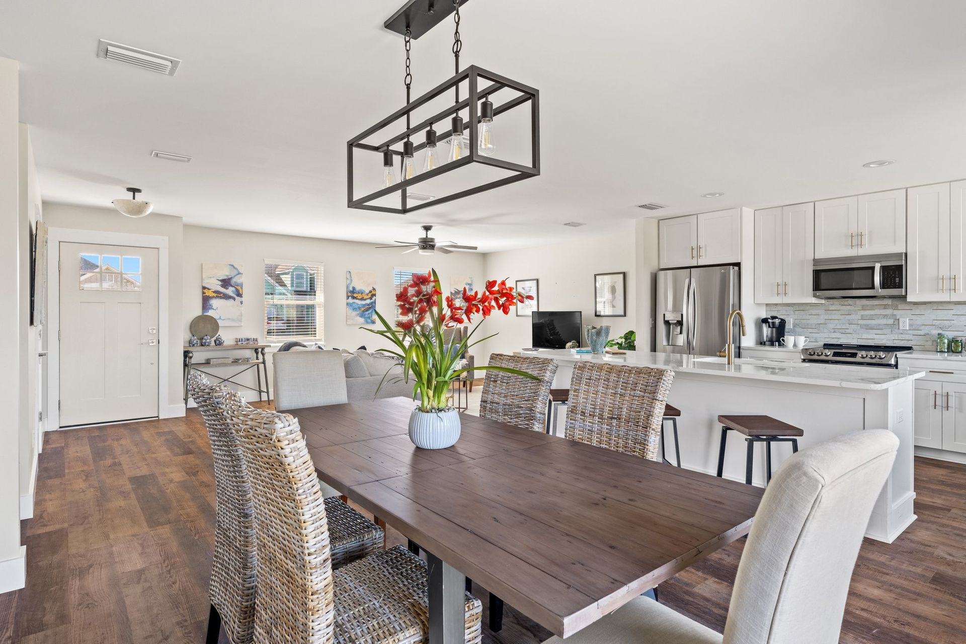 Open-concept dining room and kitchen with dark wood table, white cabinets, and stainless steel appliances.