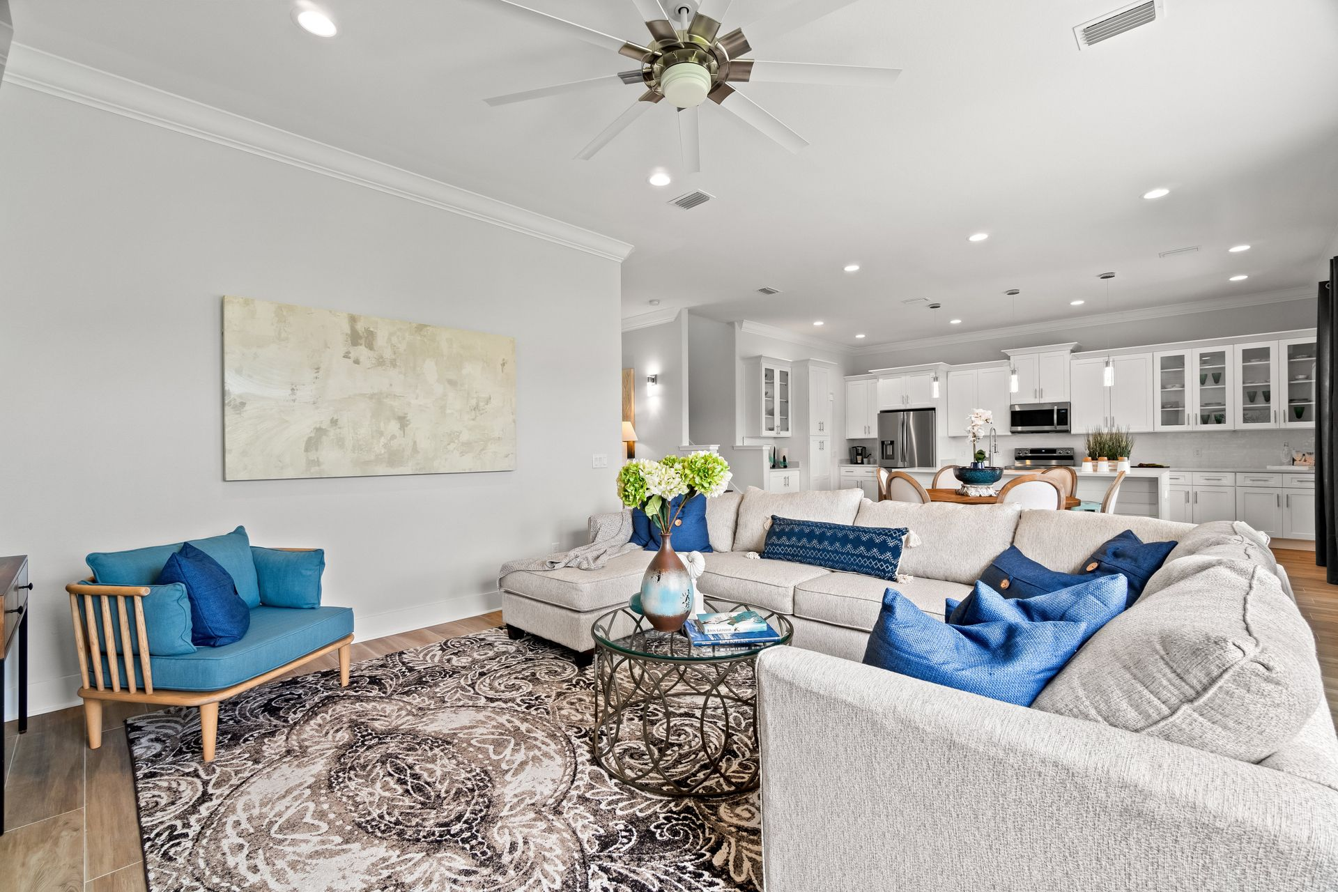 Living room with sectional sofa, blue accents, open to kitchen.