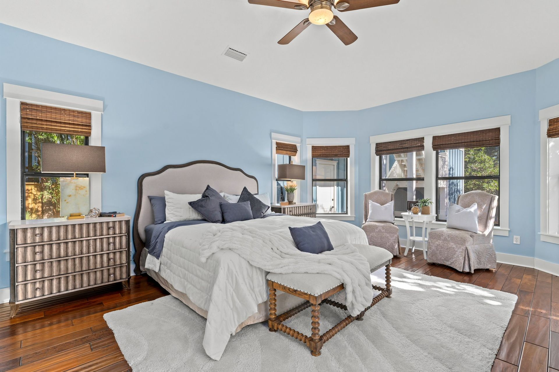 Bedroom with blue walls, hardwood floors, and a bed with white bedding.