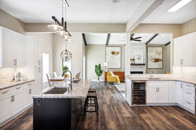 Modern kitchen with island, white cabinets, and living room in the background.