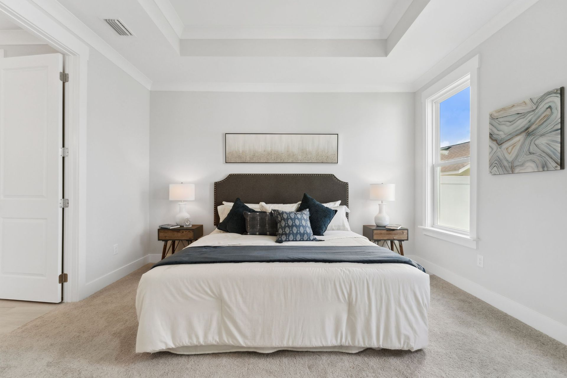 Bedroom with a bed, nightstands, and window, all in neutral tones.