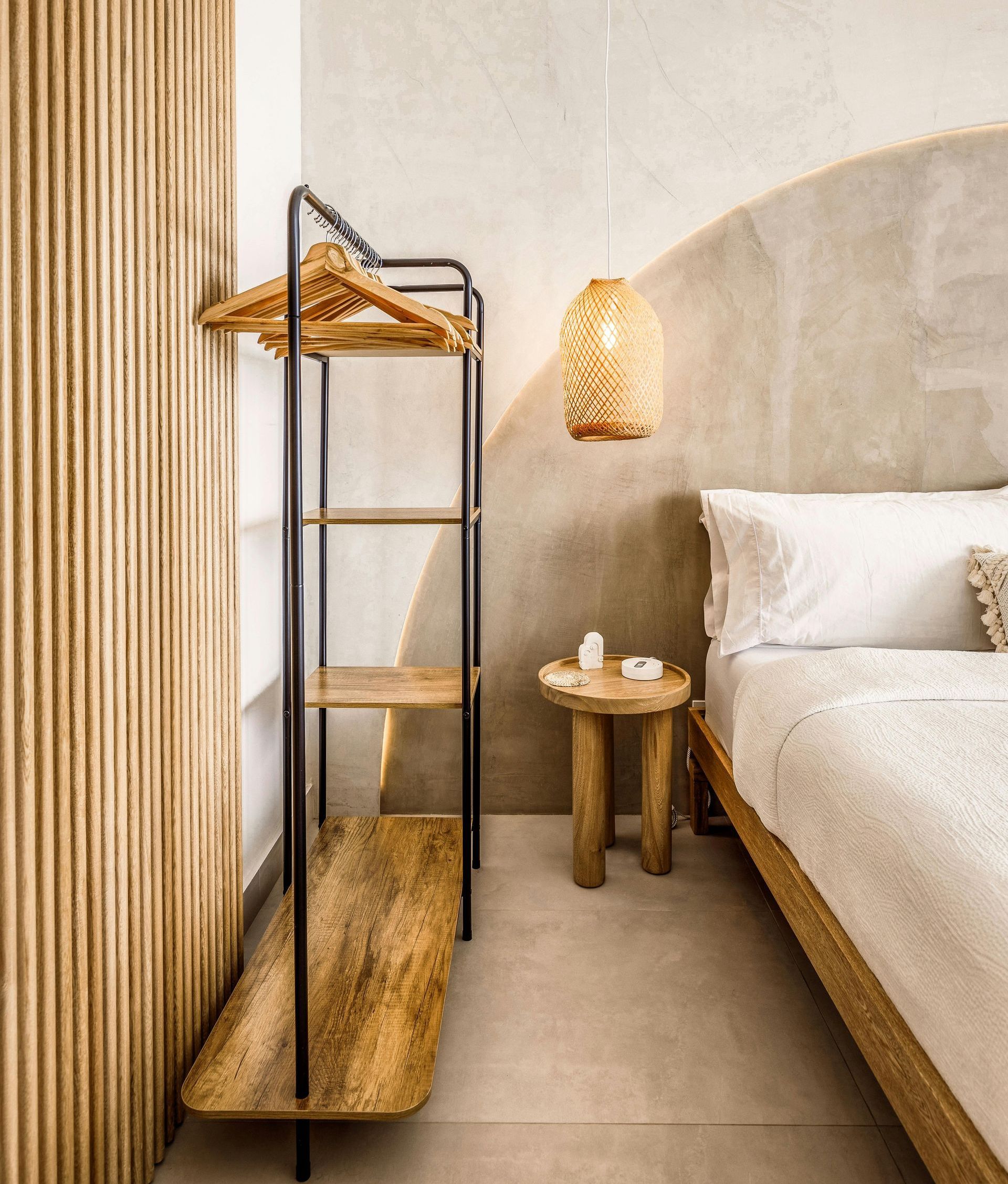A bedroom with a bed , nightstand , and clothes rack.