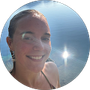 A woman is smiling in a circle with the sun shining in the background.