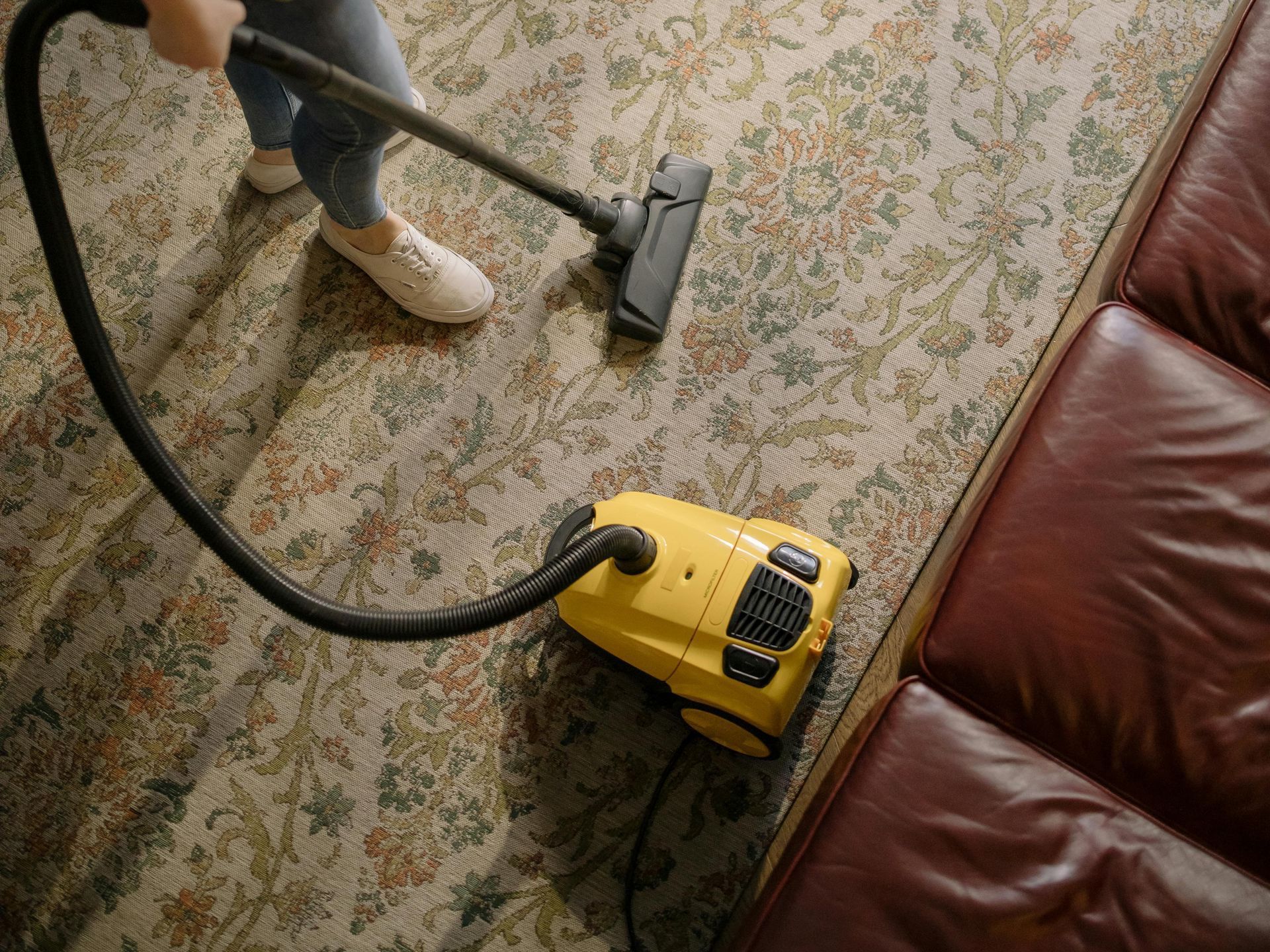 A cleaner cleaning a dirty beige carpet with a steam carpet cleaner to display our carpet cleaning option in chicago