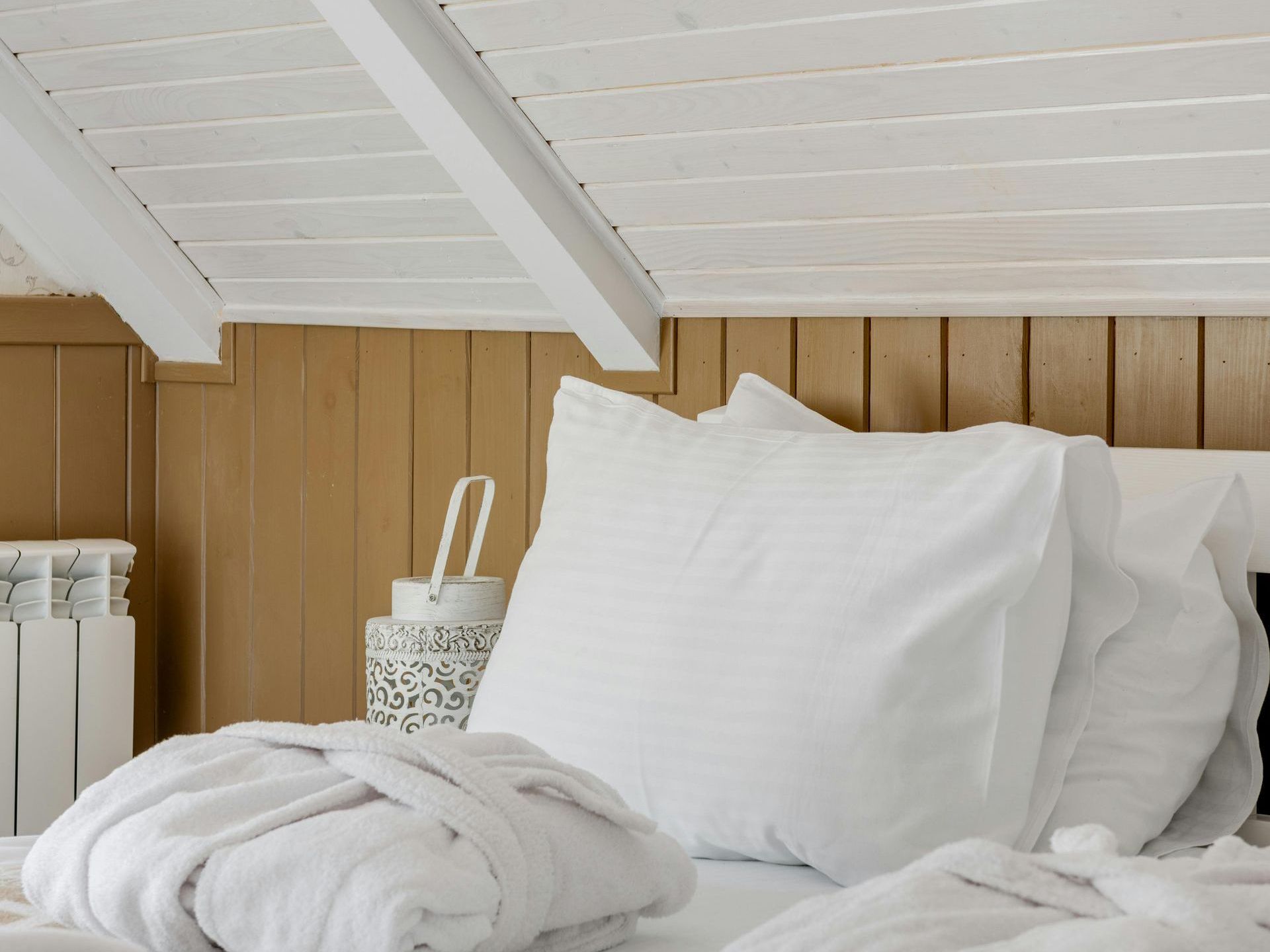 A bed with white sheets and pillows in a bedroom