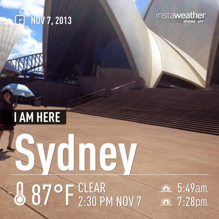A picture of a woman walking in front of a building that says i am here sydney