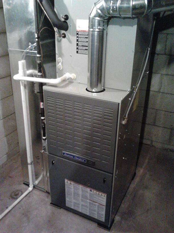 An air conditioner is sitting in a basement next to a brick wall.