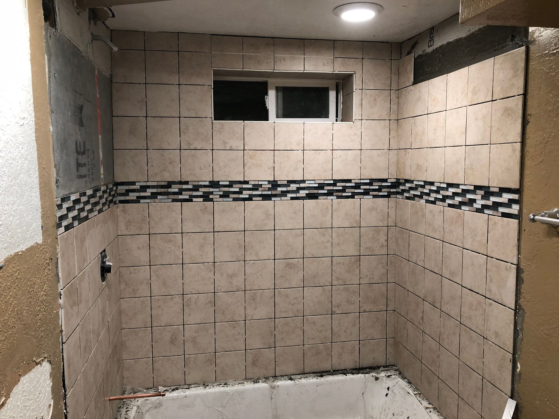 A bathroom with tiled walls and a bathtub under construction.
