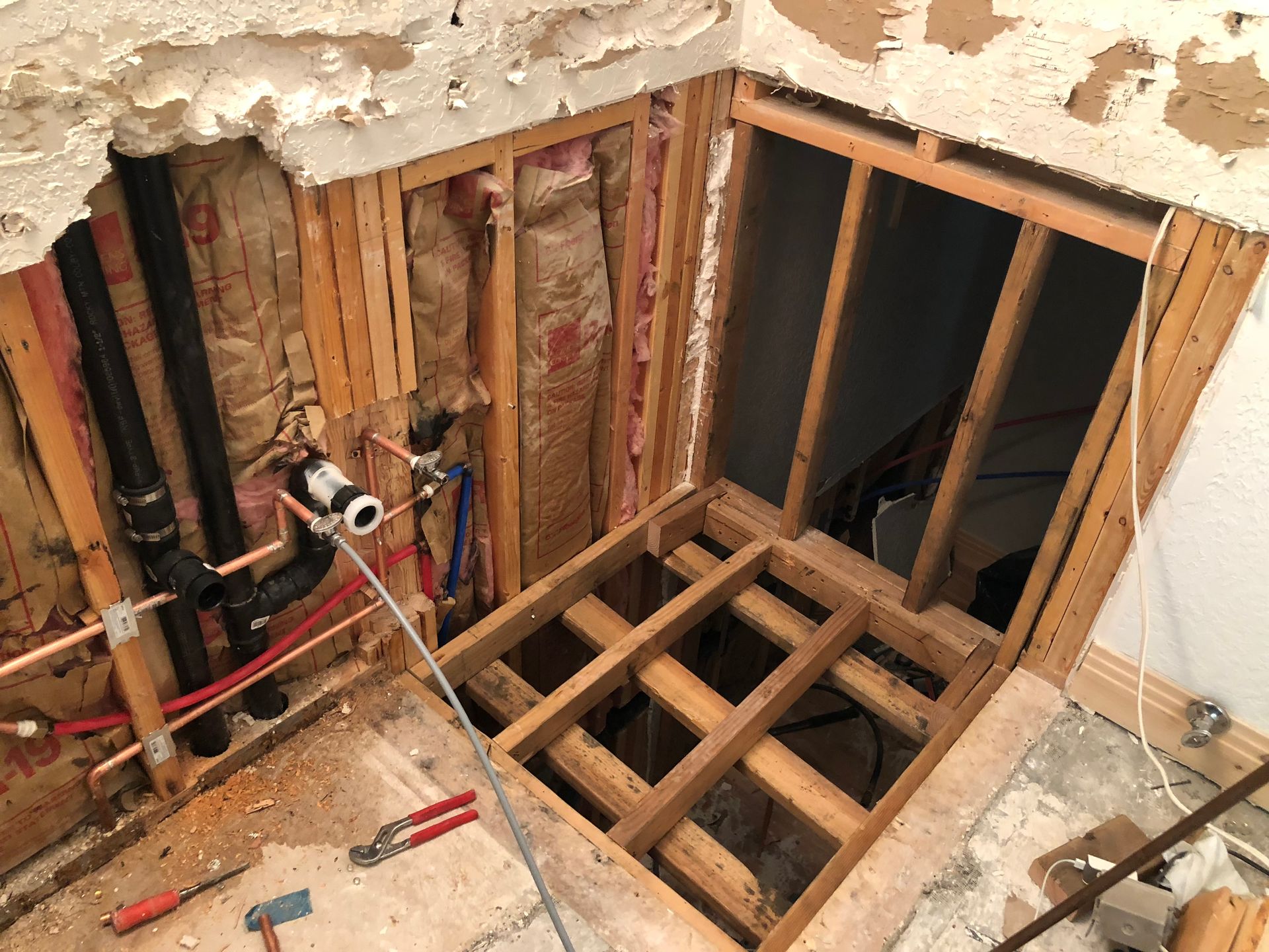 A bathroom under construction with a hole in the wall and a wooden floor.