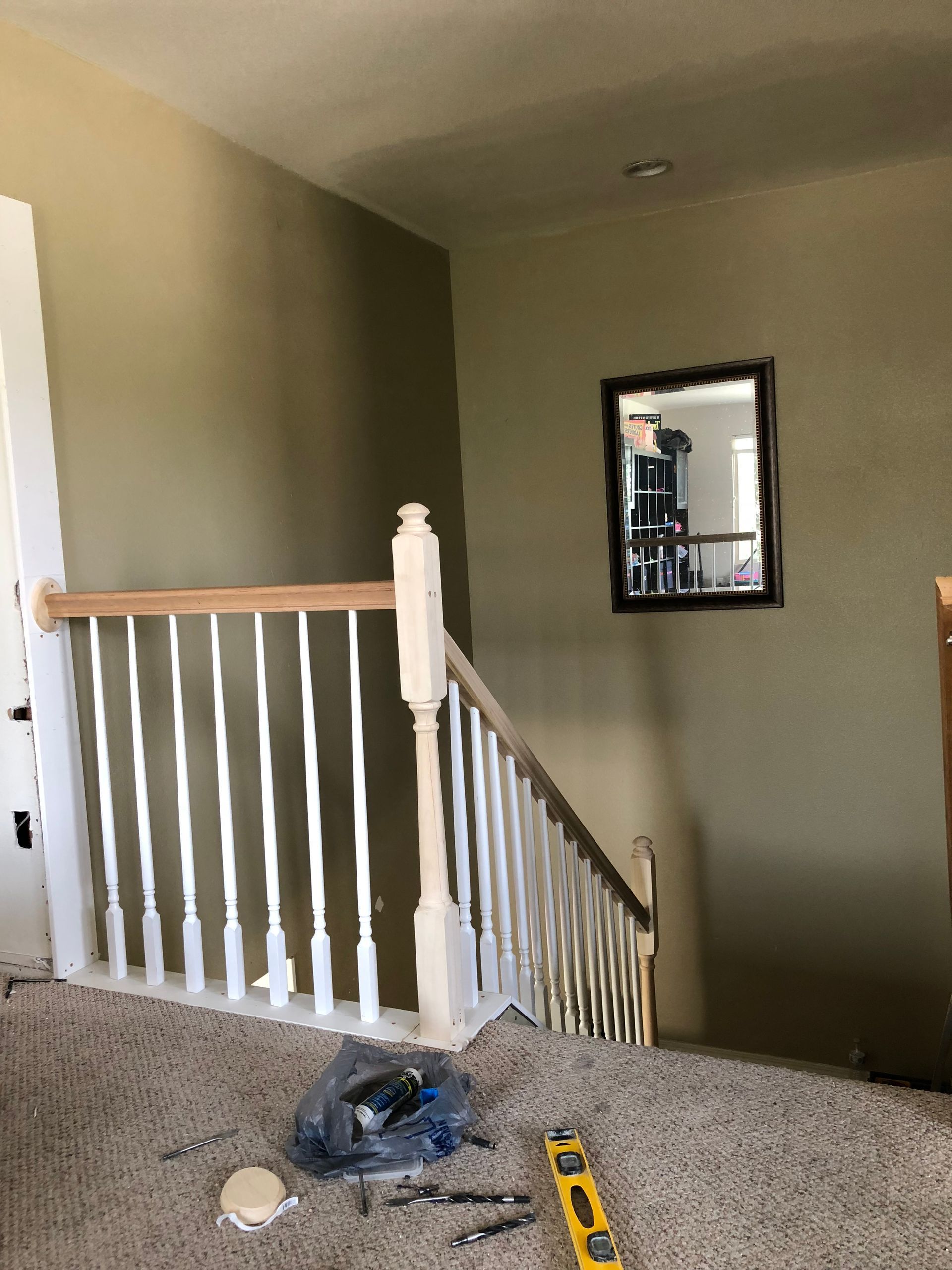 A staircase with a white railing and a mirror on the wall.