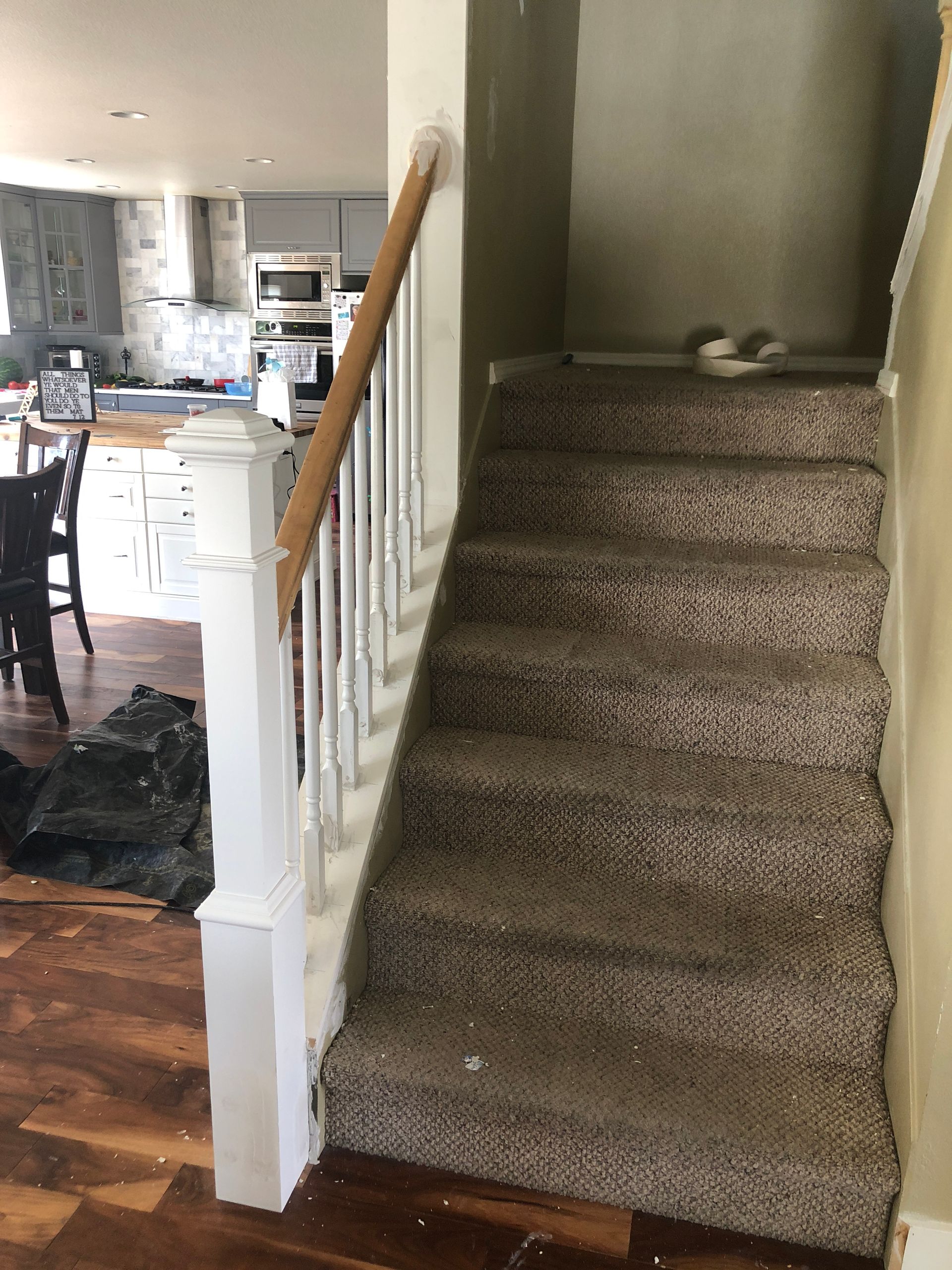 A staircase in a house with a wooden railing and carpeted steps.