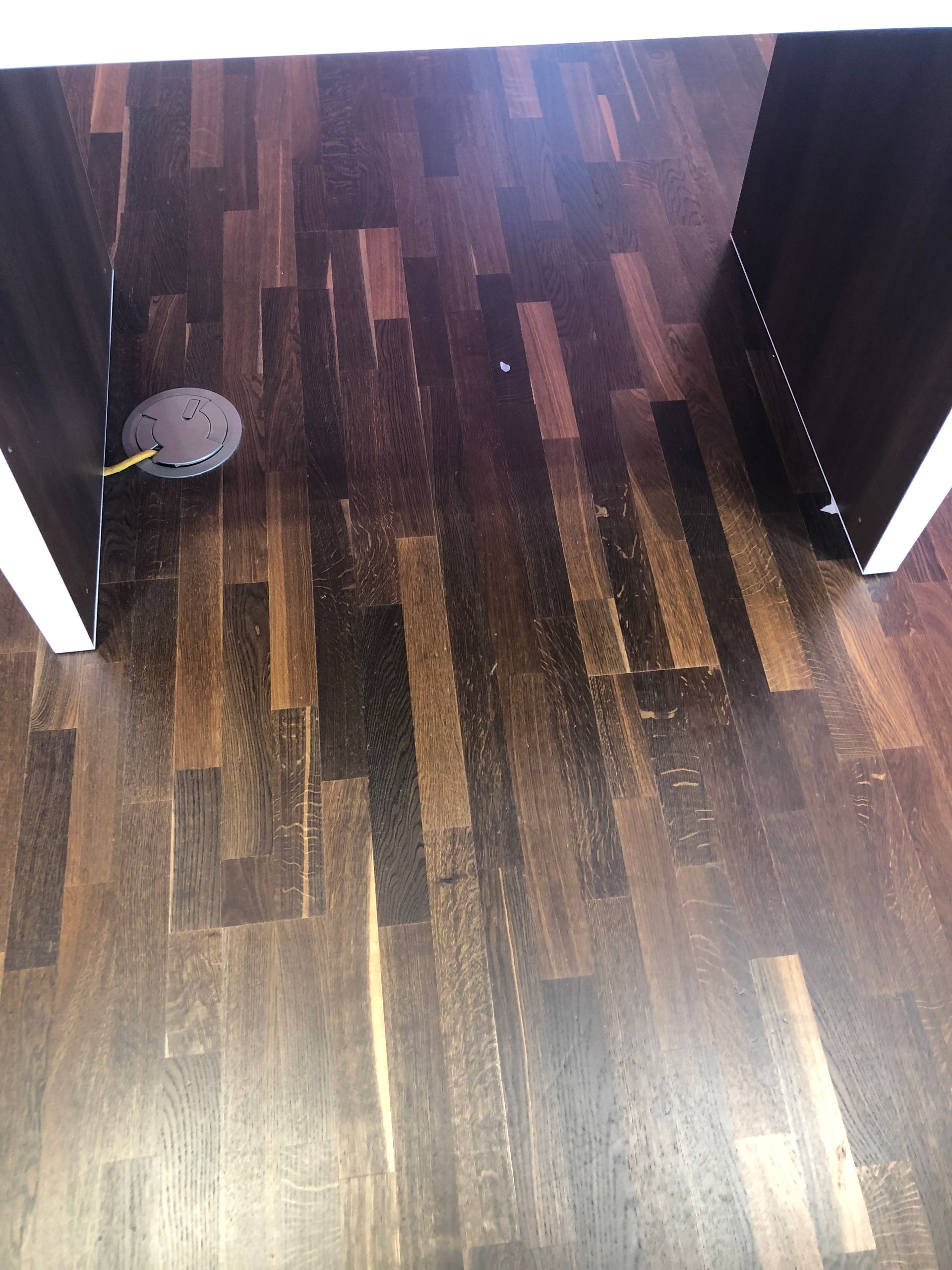 A robot vacuum cleaner is sitting on a wooden floor in a room.