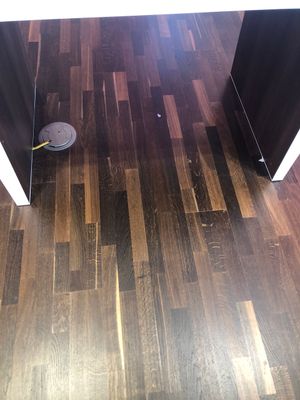 A robot vacuum cleaner is sitting on a wooden floor in a room.