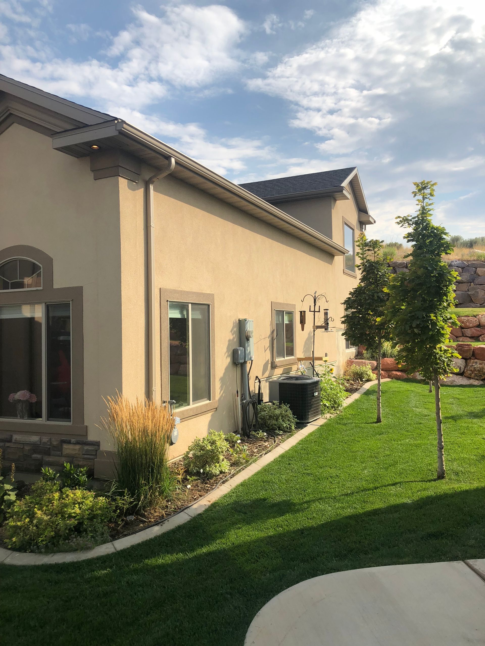 A house with a lot of windows and a lush green lawn in front of it.