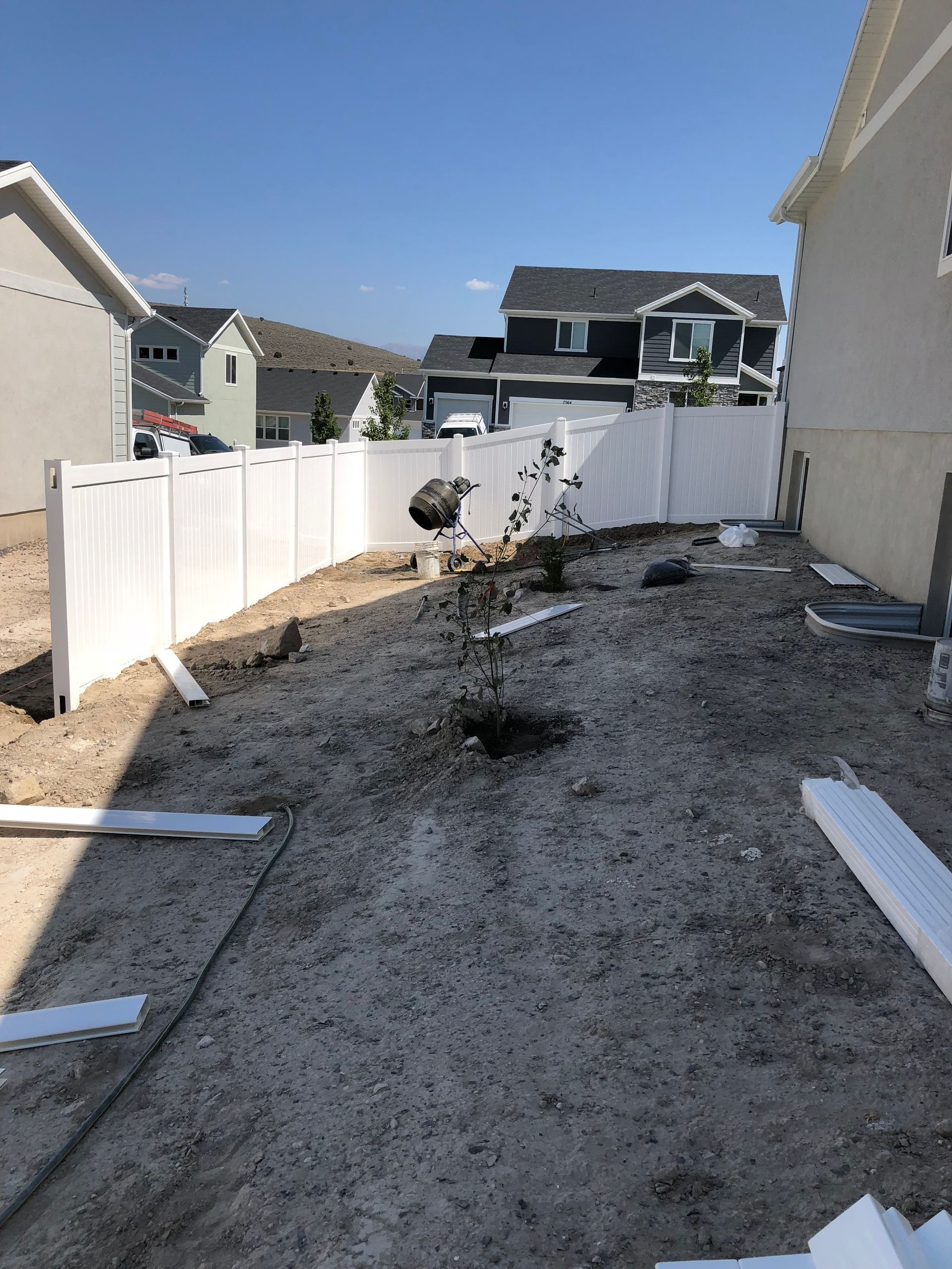 A white fence is being built in the backyard of a house.