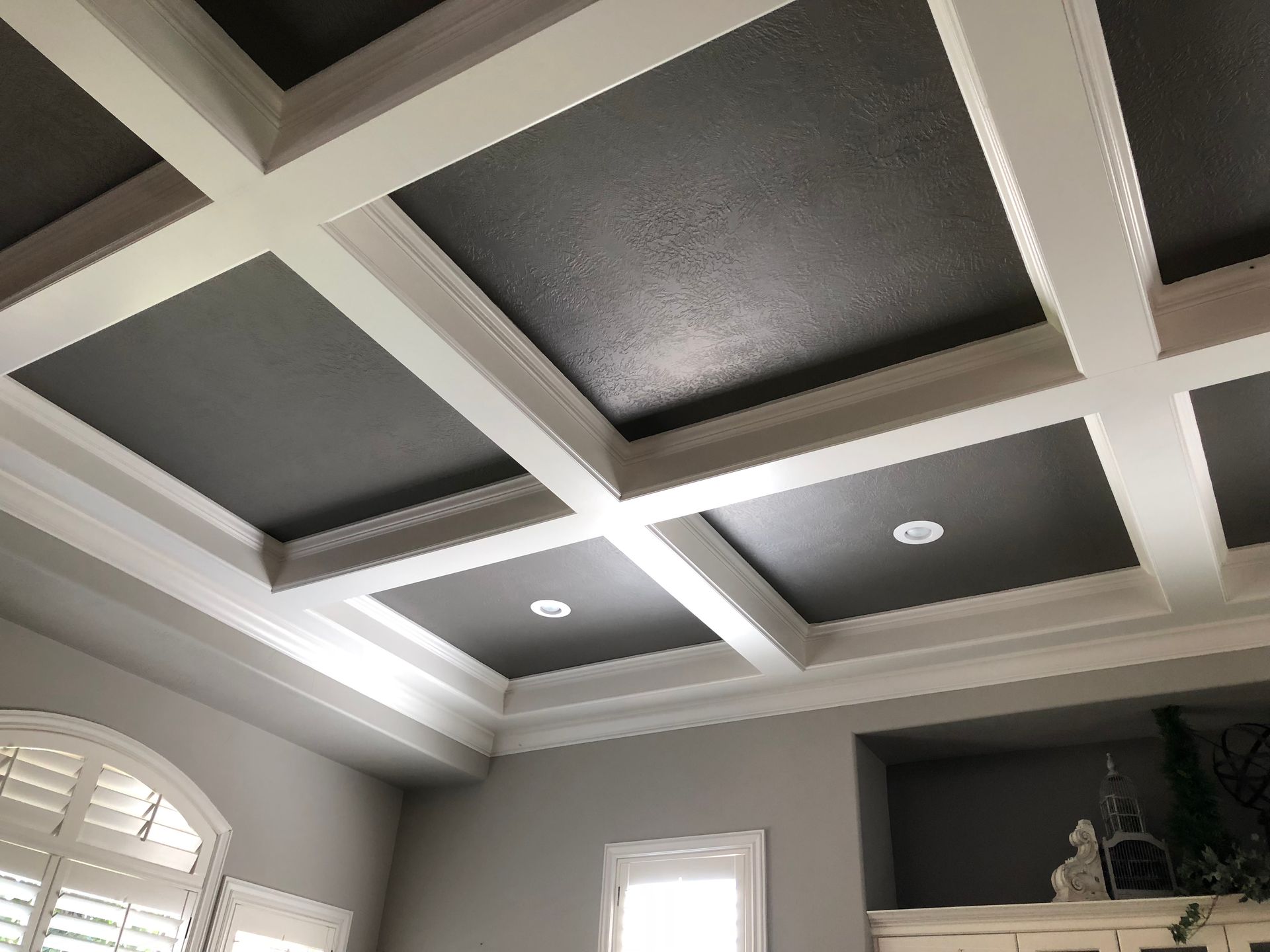 A living room with a coffered ceiling and gray walls.