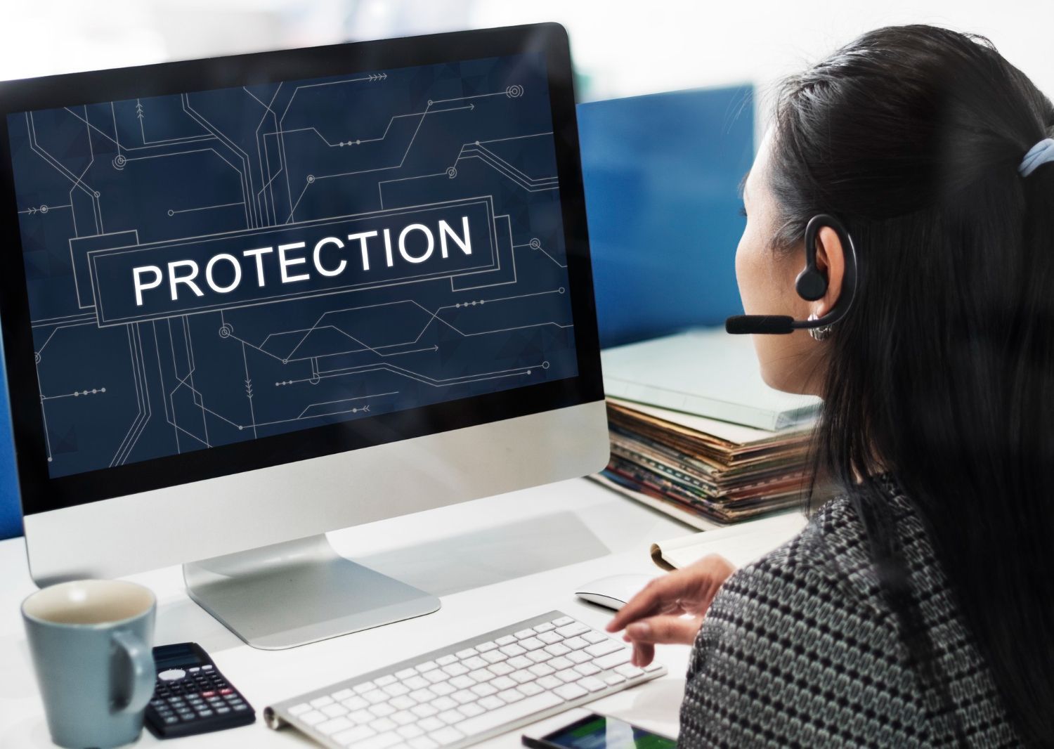 A woman is sitting in front of a computer with the word protection on the screen.