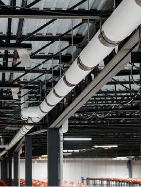 A warehouse with a lot of pipes hanging from the ceiling