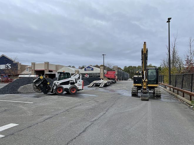 A bulldozer and an excavator are parked in a parking lot.