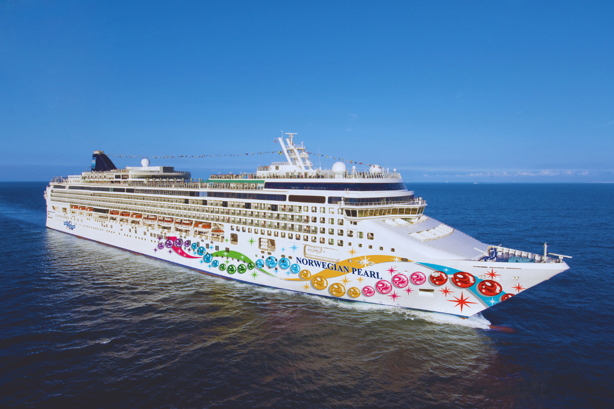 Large white cruise ship with colorful artwork sailing on calm blue ocean under a clear sky