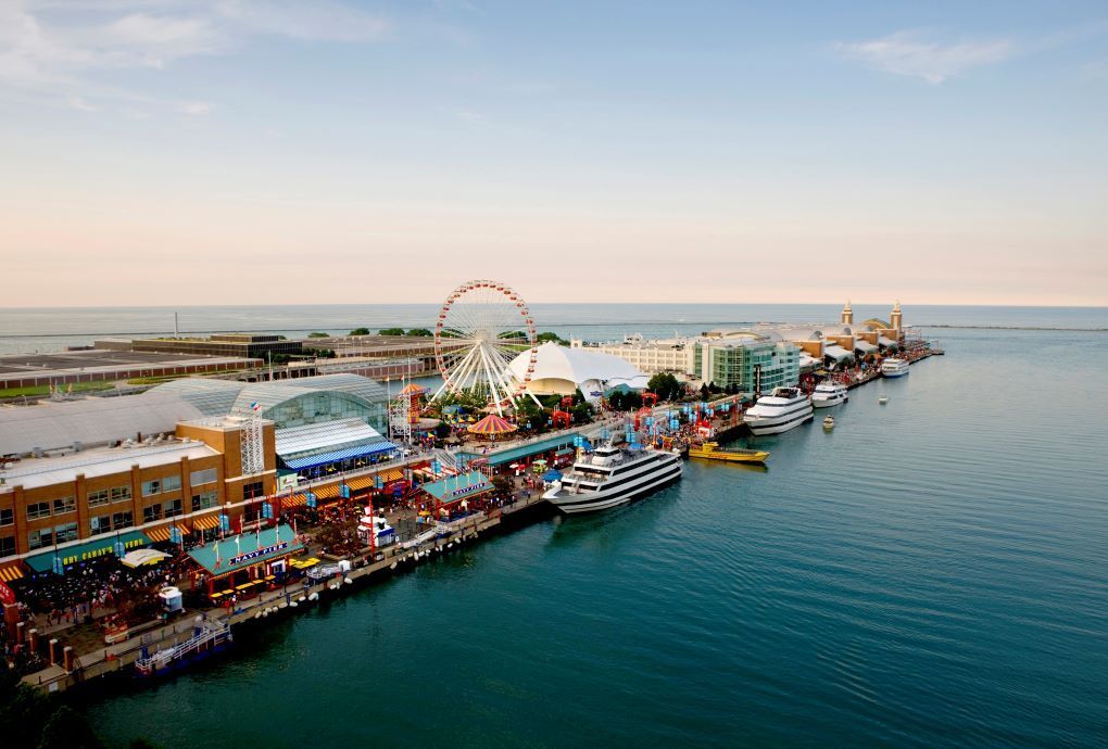 Aerial view of Navy Pier, Chicago, with Ferris wheel, boats, and buildings along the water.