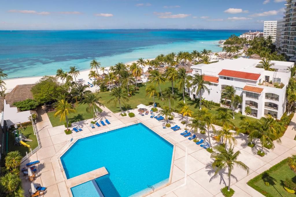 Pool and resort near a turquoise ocean and white sand beach in Cancun, Mexico.