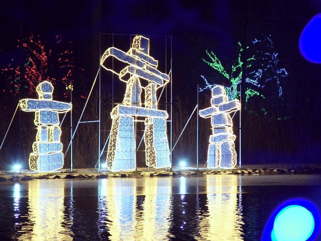 Illuminated Inukshuks reflected in water.