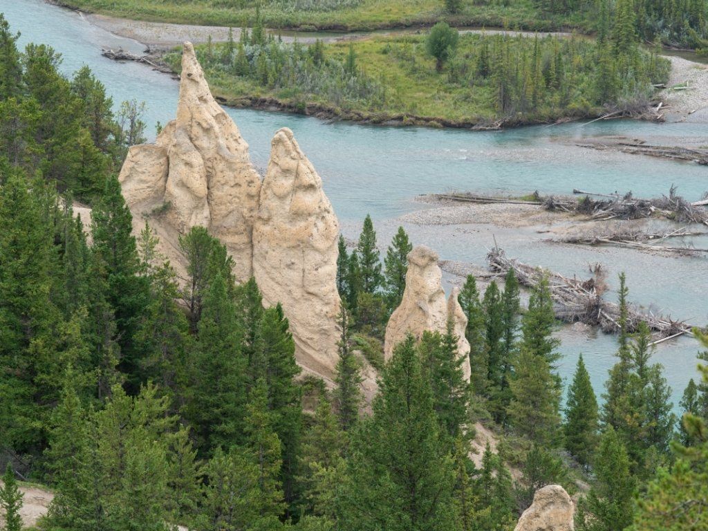Tall, eroded rock formations in a forest next to a river.