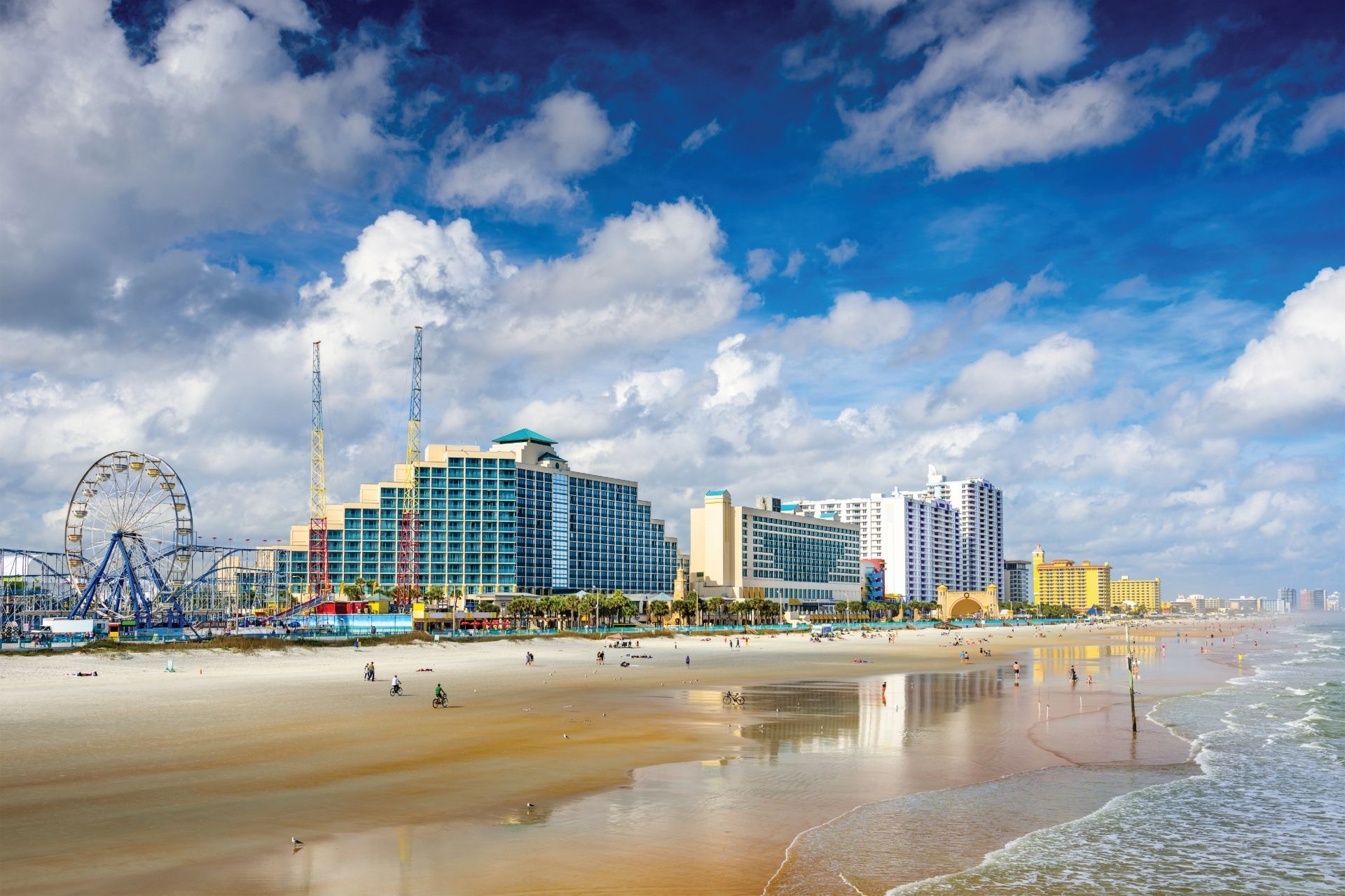 Daytona Beach skyline with Ferris wheel, hotels, beach, and blue sky.
