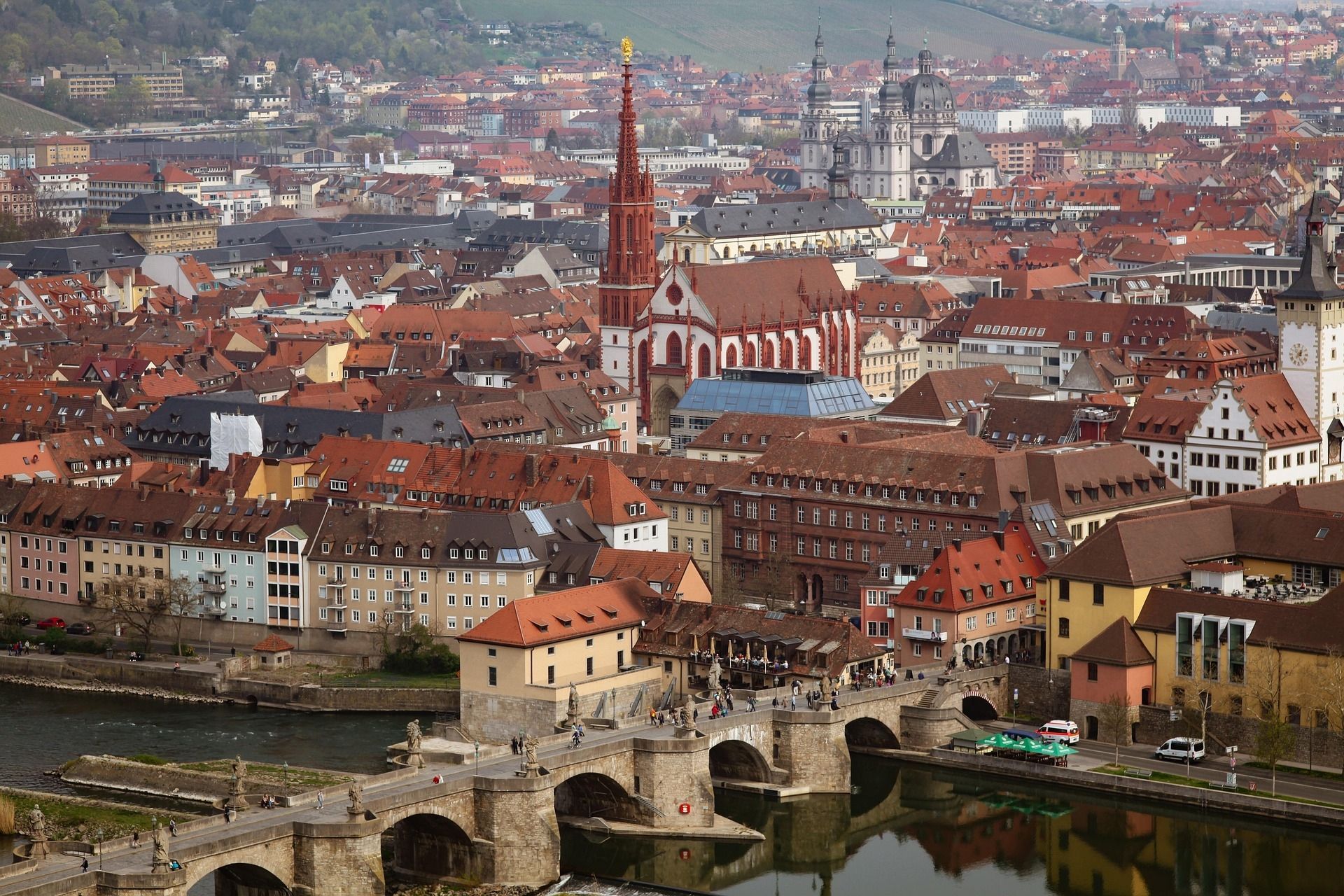 Würzburg, Germany, cityscape with red church spire, bridge over river, and colorful buildings.