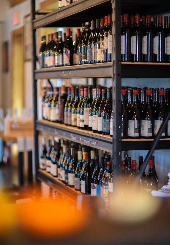 Wine bottles on black shelves in a store.