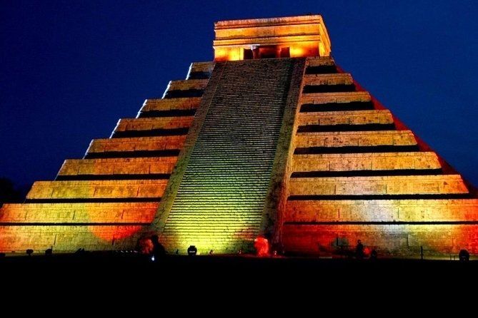 Illuminated Mayan pyramid at night, with warm orange and yellow lighting.