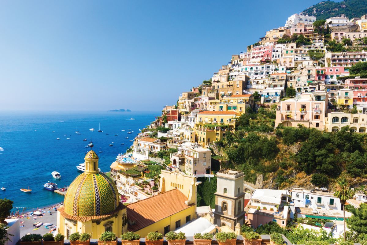 Colorful cliffside houses overlooking a blue sea, with a domed church in the foreground.