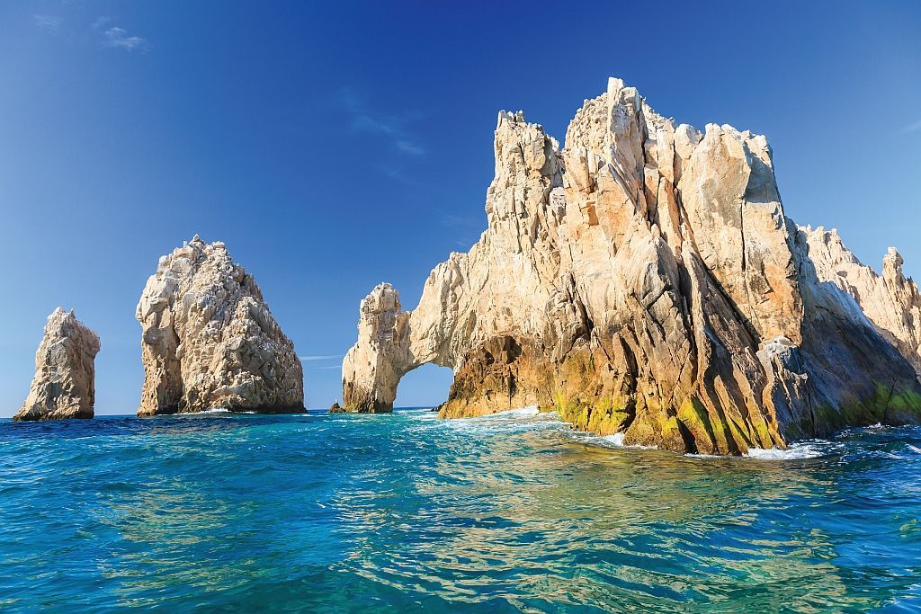 Rocky sea stacks rising from turquoise water under a clear blue sky.