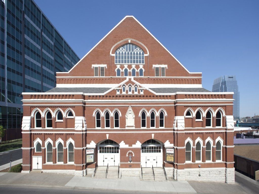 Ryman Auditorium in Nashville, TN, a brick building with white trim, featuring a peaked roof and arched windows.