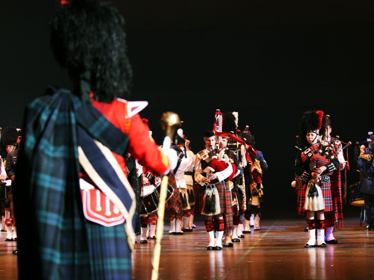 Scottish bagpipe band in traditional kilts and uniform on stage.