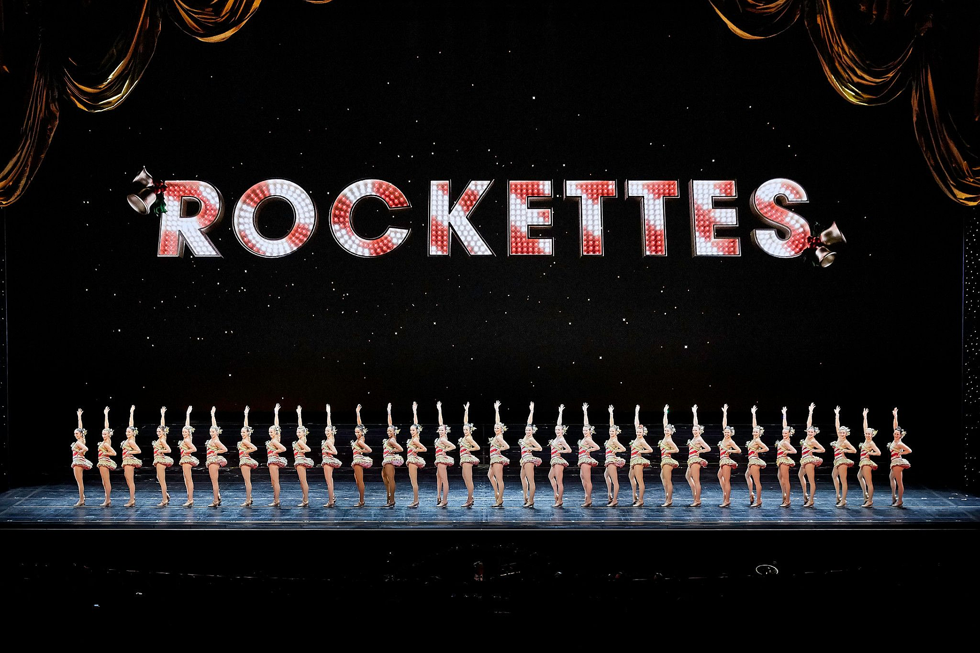 Rockettes perform on stage, spelling 
