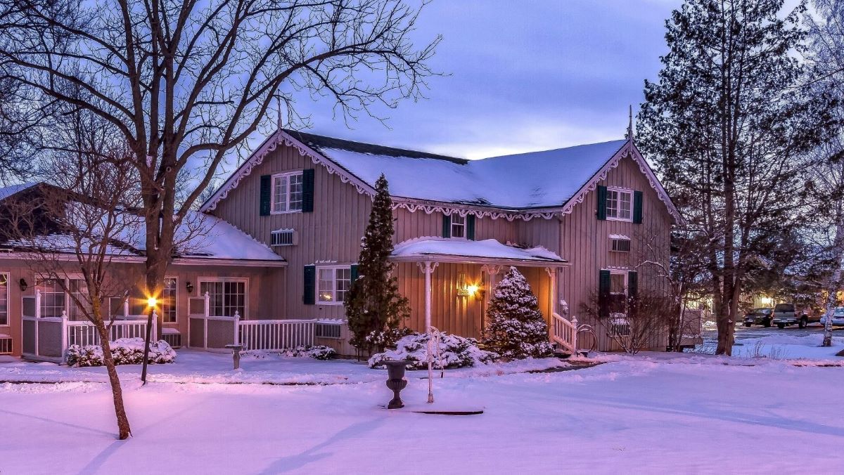 Snowy house with Christmas lights on a winter evening; a cozy scene.