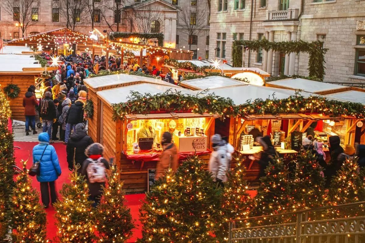 Festive Christmas market with glowing stalls, red carpet, and people shopping in snowy streets