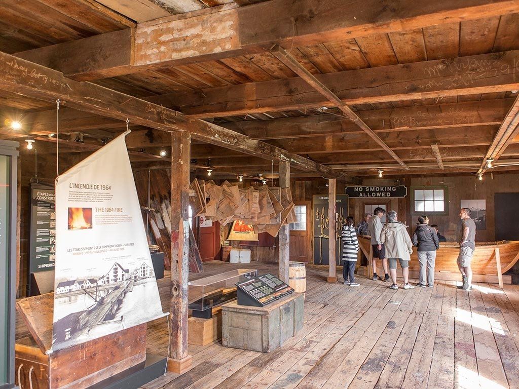 Inside museum, people view exhibits, wooden beams above.