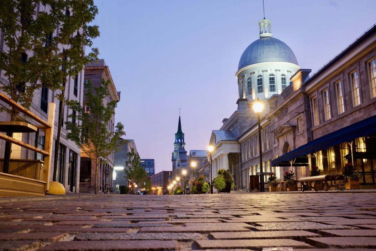 Cobblestone street at dusk with a lit cathedral dome and historic buildings lining the avenue