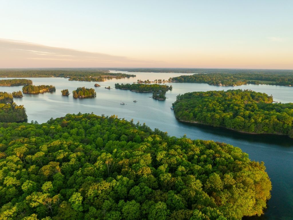 Aerial view of a lush green island lake at sunrise with calm water and scattered islets