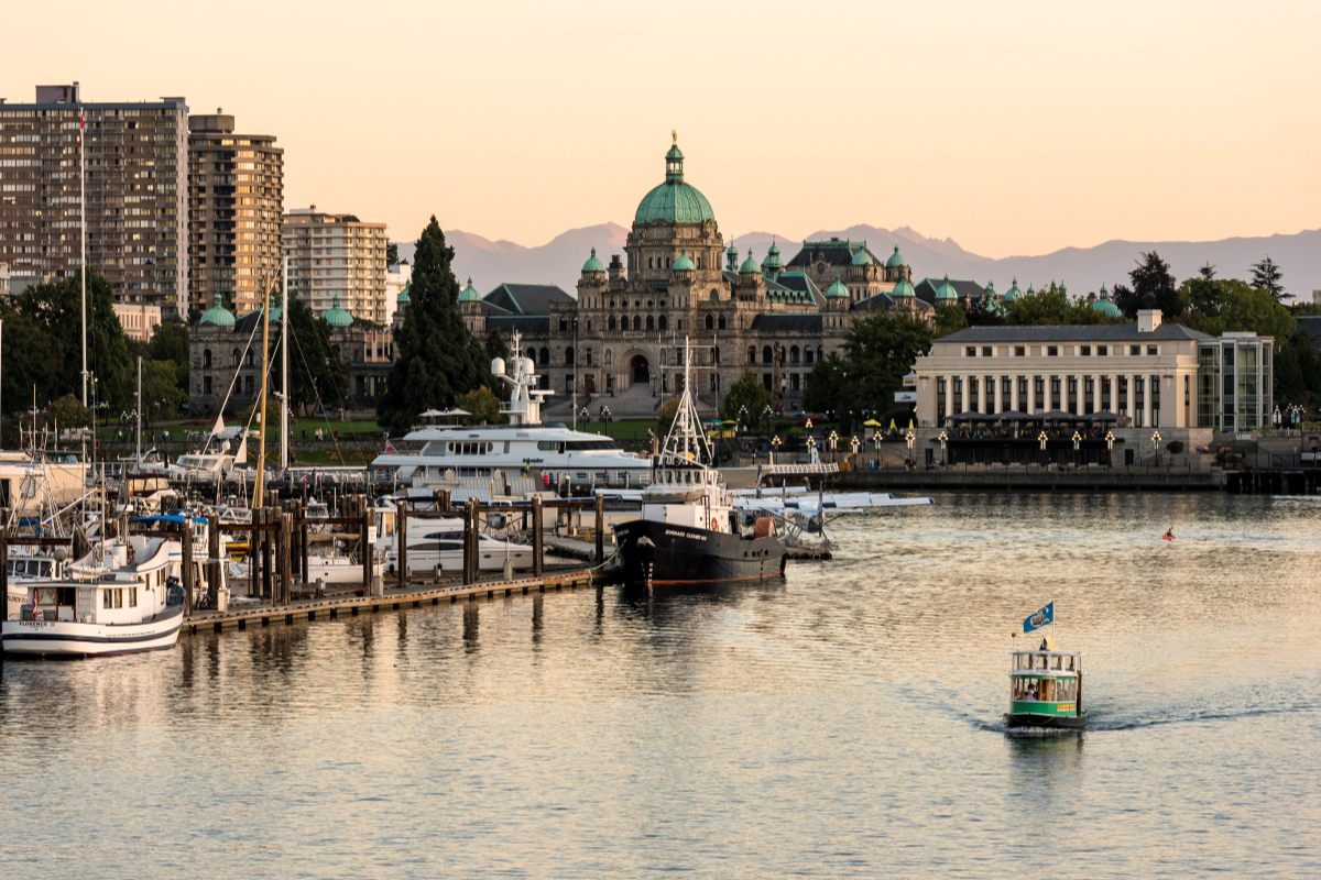 Boats on water near a dock with the Parliament Buildings in Victoria, BC in the background.