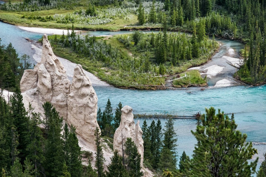 Blue river winding through green forest beside pale rocky spires