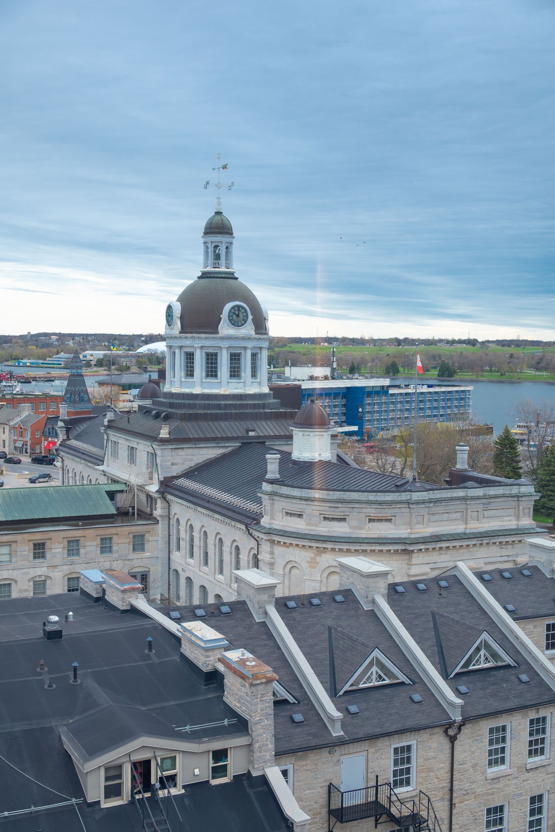 Historic waterfront cityscape with a white-domed clock tower and stone buildings under a cloudy blue sky