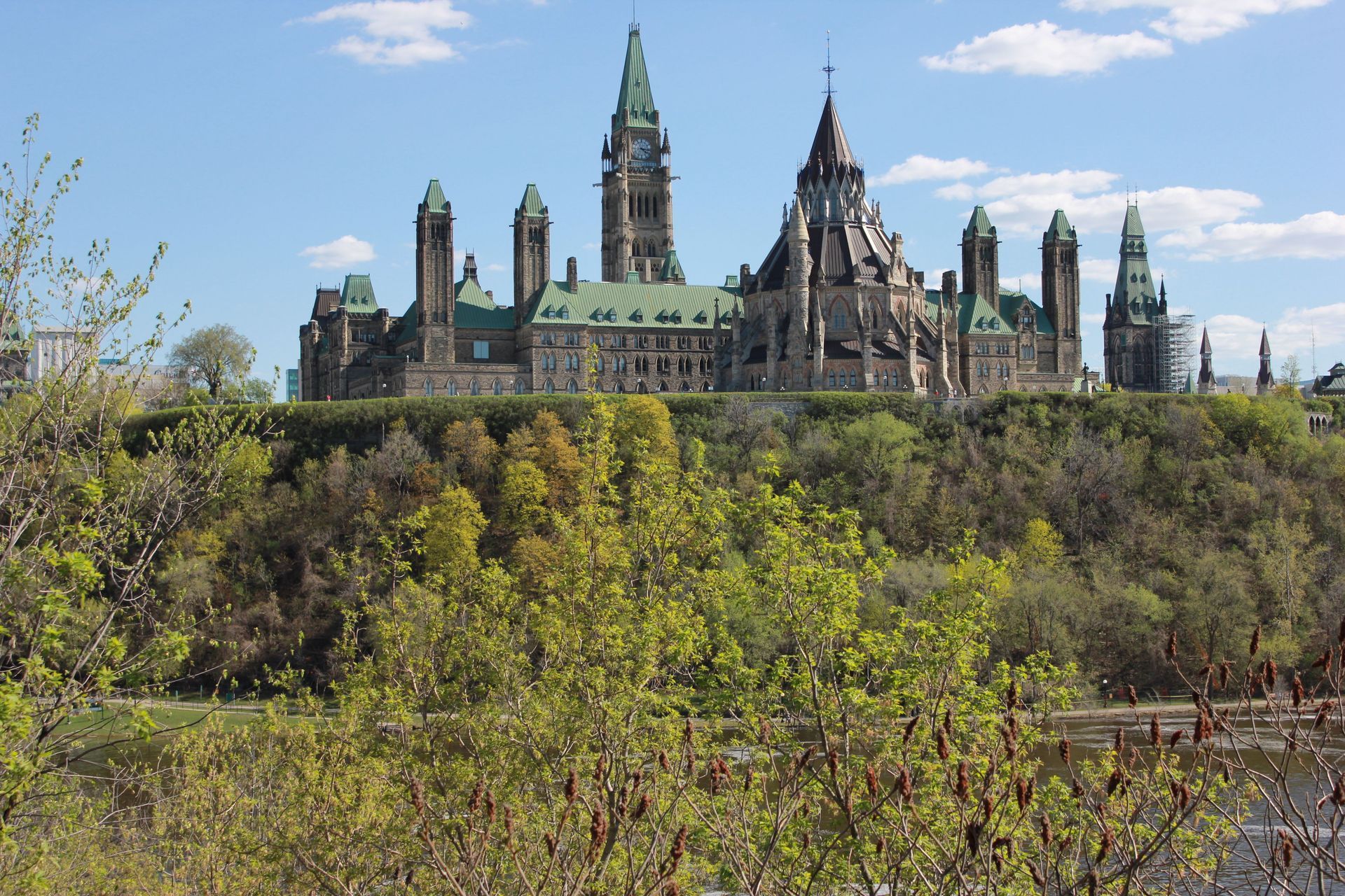 Historic Parliament building on a hill above green trees under a blue sky