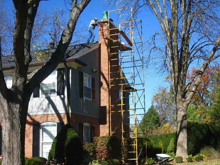 A man is working on a chimney on top of a scaffolding