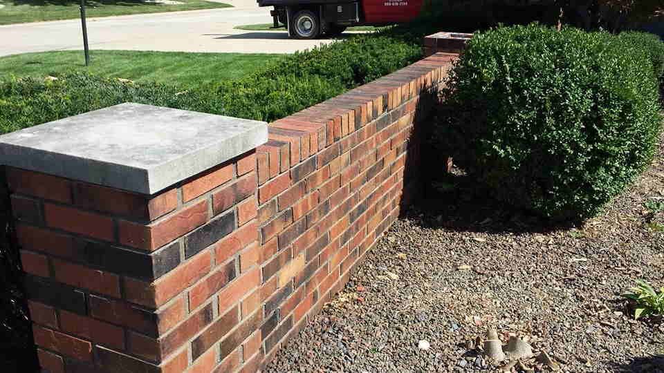A red truck is parked in front of a brick wall.
