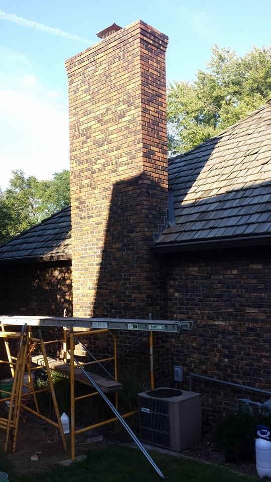 A brick chimney is being repaired on the side of a house.